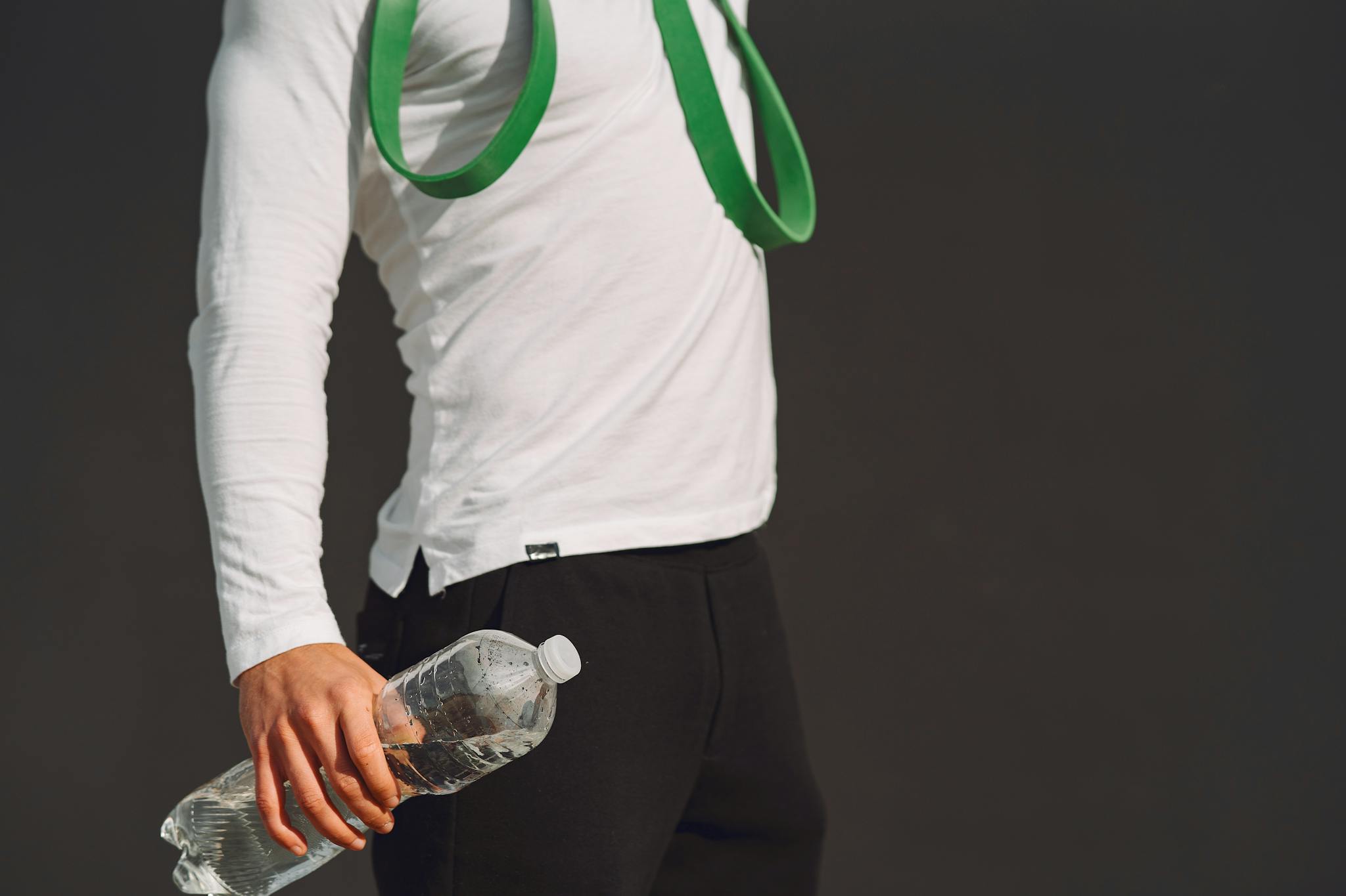 An individual holds a water bottle and fitness band, showcasing a healthy lifestyle and exercise readiness.