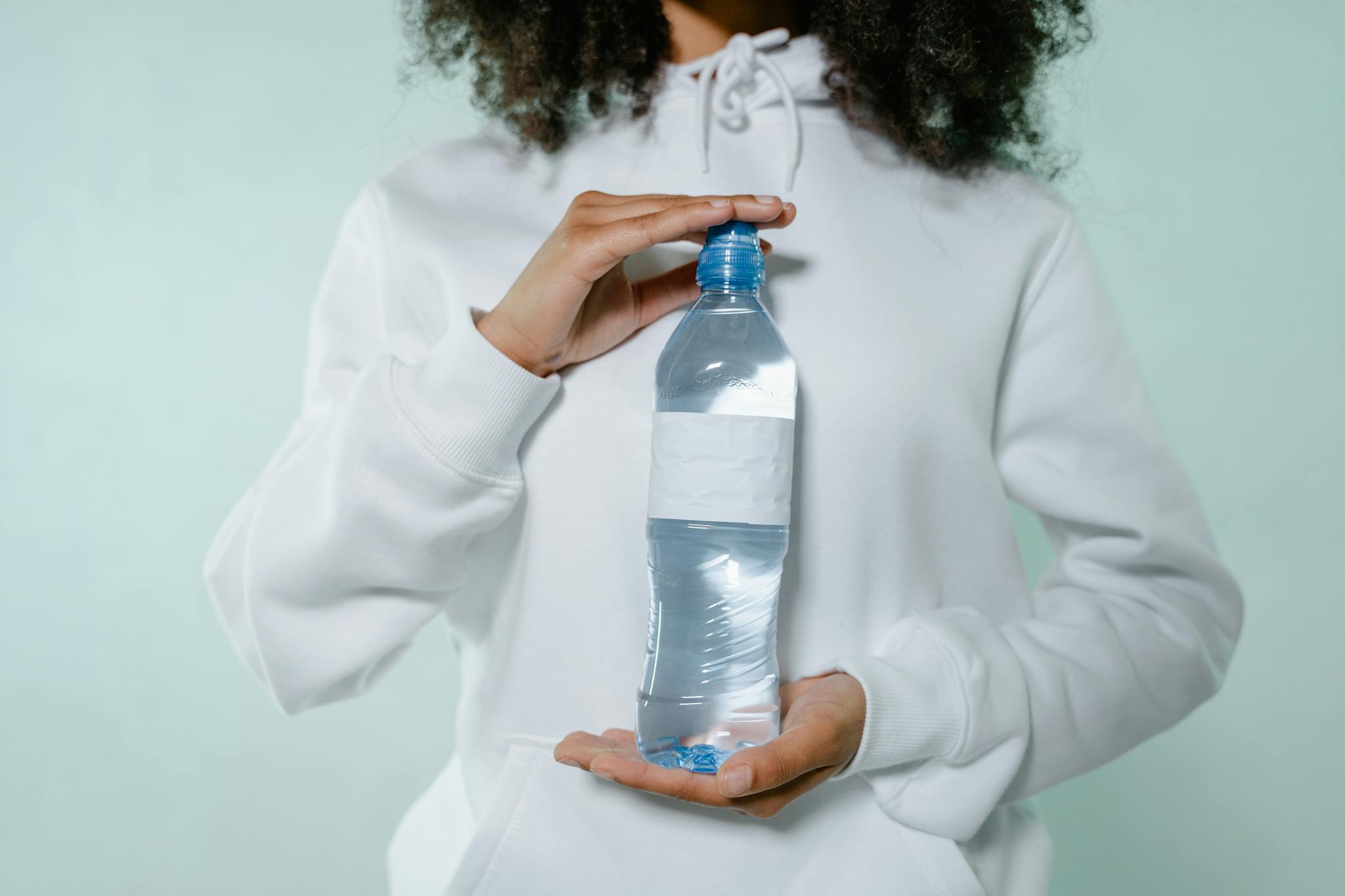 Persona hidratándose con agua, hábitos saludables de bienestar, mejorar energía diaria