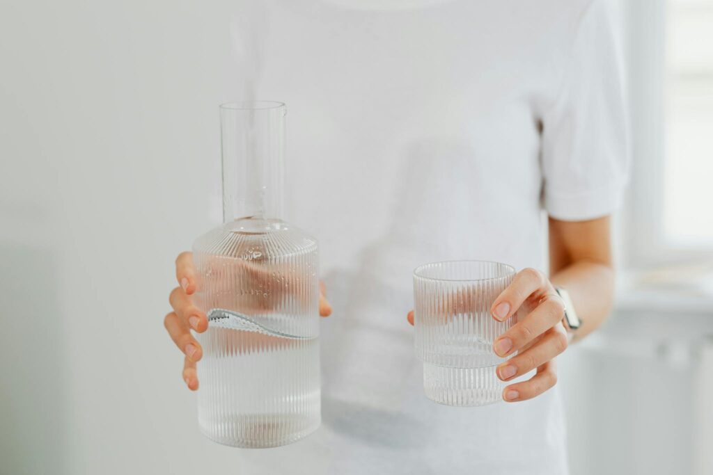 Persona hidratándose con agua, hábitos saludables de bienestar, mejorar energía diaria