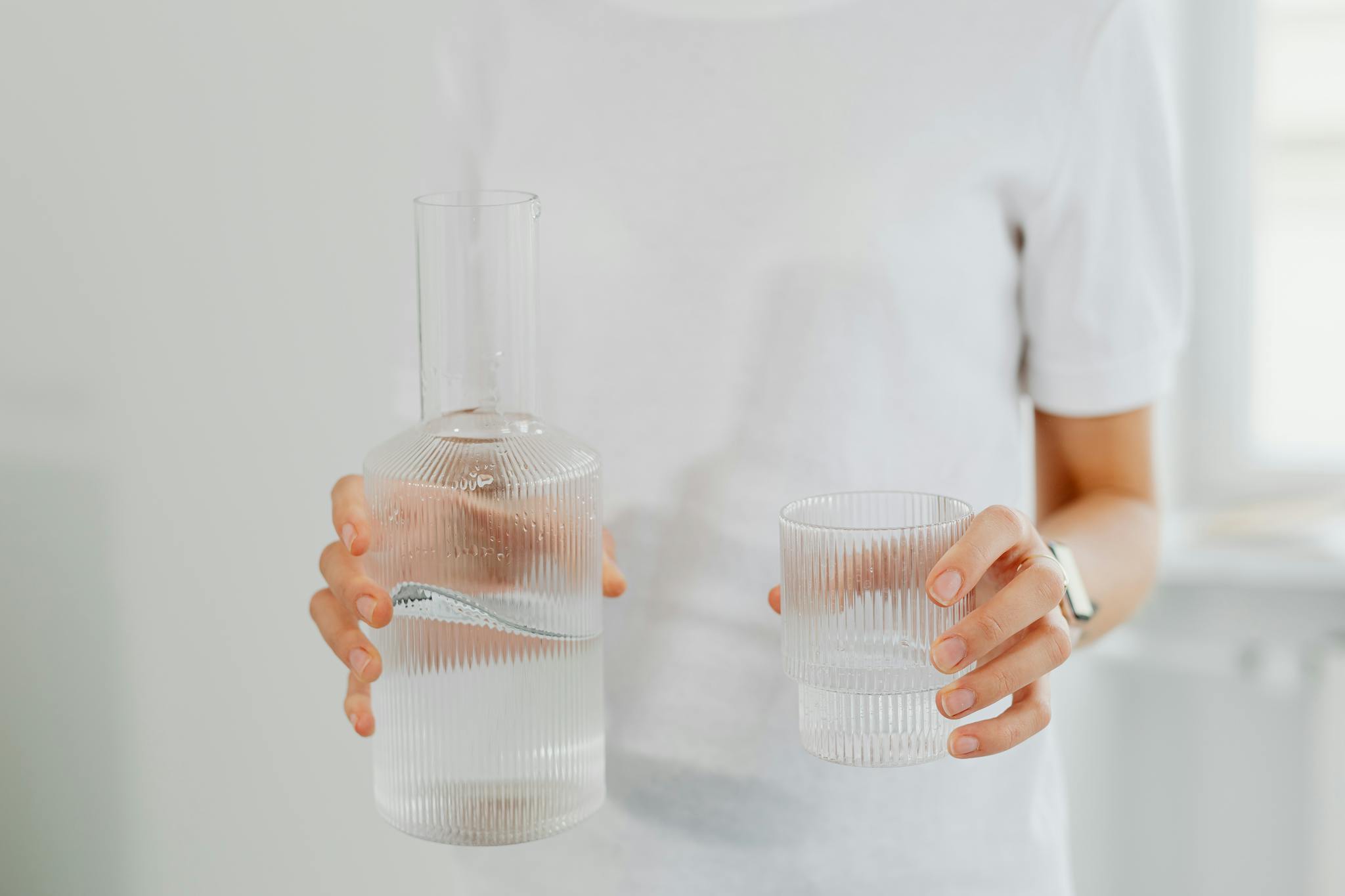 Persona hidratándose con agua, hábitos saludables de bienestar, mejorar energía diaria